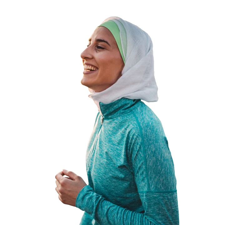 A middle-eastern woman walking outdoors wearing a workout jacket and a head scarf